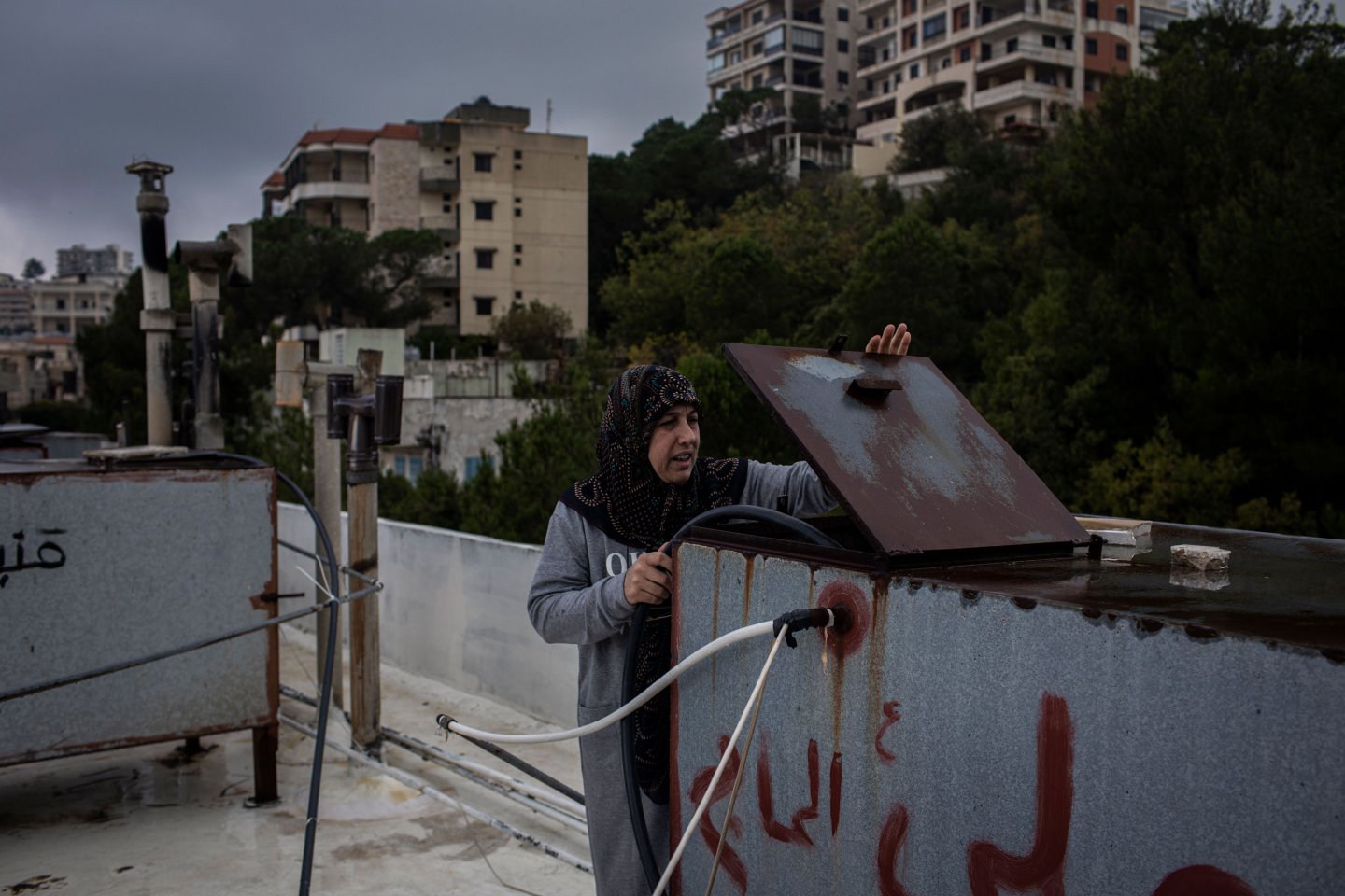 50-year-old Rhanya Ghamloush checks the private water tank on the roof of her home. As is often the case, it is empty.